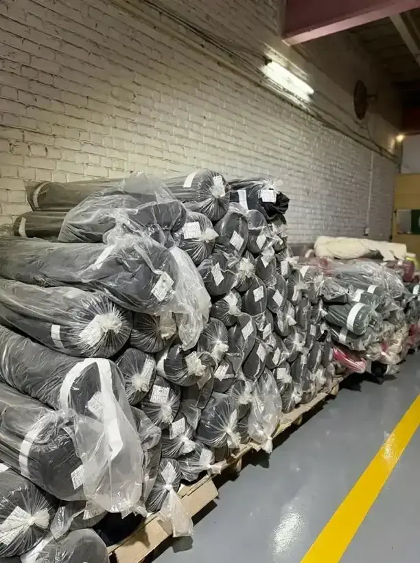Rolls of grey fabric stored on pallets in the SAS Agencies warehouse in Faisalabad
