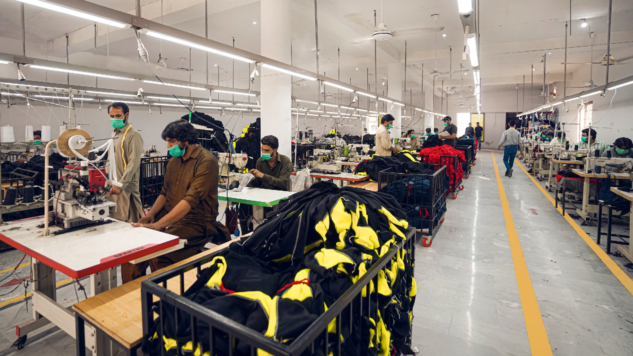 Stitching floor with rows of industrial sewing machines producing workwear at SAS Agencies